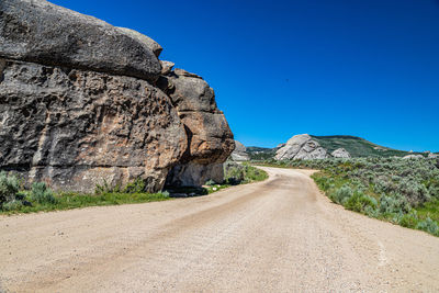 Road amidst rocks against clear blue sky