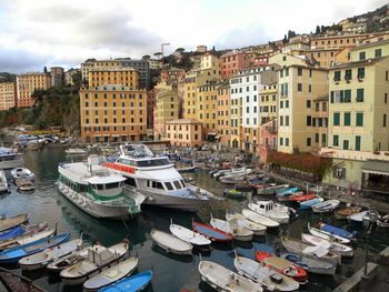 High angle view of boats moored at harbor by buildings in city