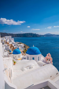 Buildings in sea against blue sky