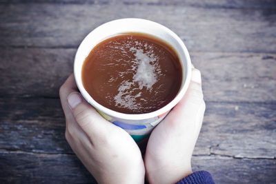 Close-up of hand holding coffee cup on table