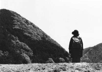 Rear view of man standing on mountain against clear sky