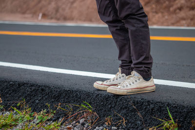 Low section of man standing on roadside