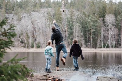 Father throwing logs into the sea with his kids whilst hiking