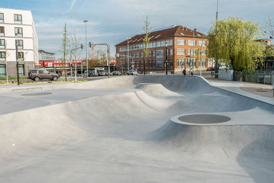 Skateboardpark  and road by buildings in city against sky
