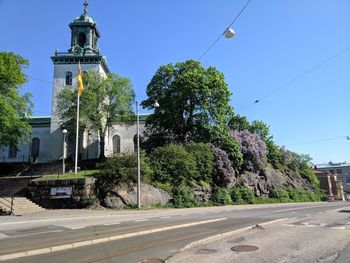 Street amidst trees and buildings against sky