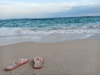 High angle view of shoes on sand at beach against sky