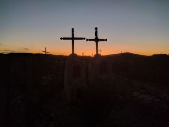 Silhouette cross against clear sky during sunset
