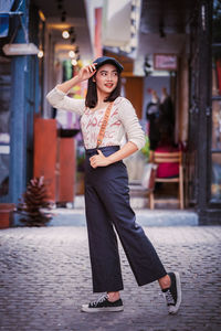 Portrait of smiling young woman standing against built structure