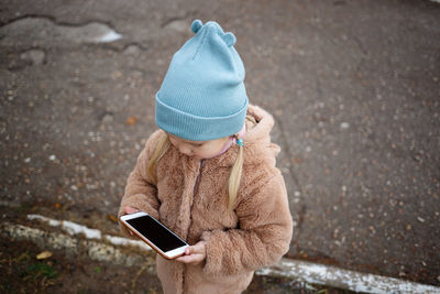 Rear view of boy using mobile phone in winter