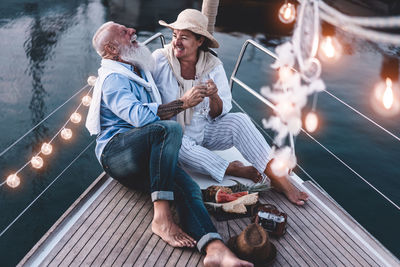 High angle view of cheerful couple sitting on boat at sunset