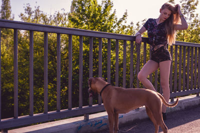 Young woman standing by dog on footbridge