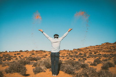 Low angle view of person standing on landscape against clear blue sky