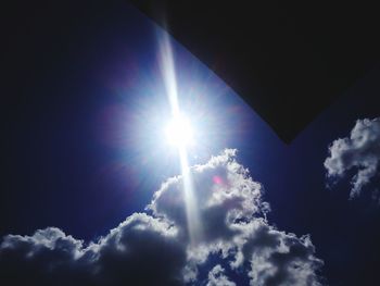 Low angle view of sun shining through clouds