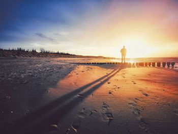 Silhouette man on beach against sky during sunset