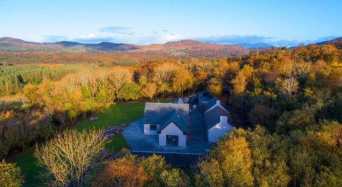 House amidst trees and plants against sky during autumn