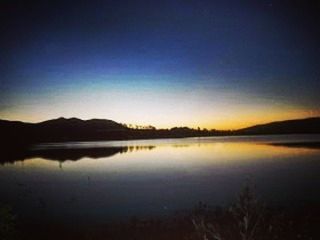 water, reflection, tranquil scene, lake, tranquility, scenics, clear sky, beauty in nature, copy space, mountain, nature, silhouette, standing water, idyllic, waterfront, sunset, calm, dusk, mountain range, sky