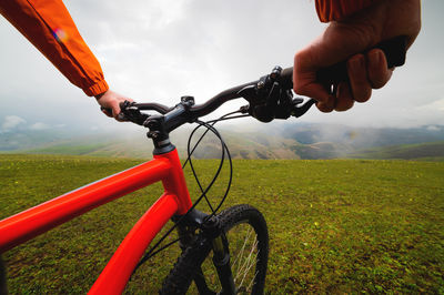 Hands hold the steering wheel of a bicycle while standing on a green meadow. a look through the eyes