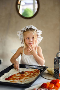 Little girl cooking pizza in the kitchen