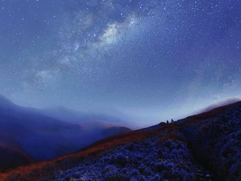 People on mountain against star field at night