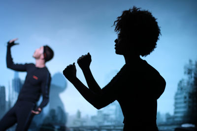 Side view of silhouette woman standing against sky