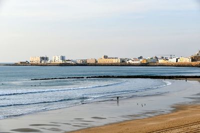 Sea by buildings against sky in city