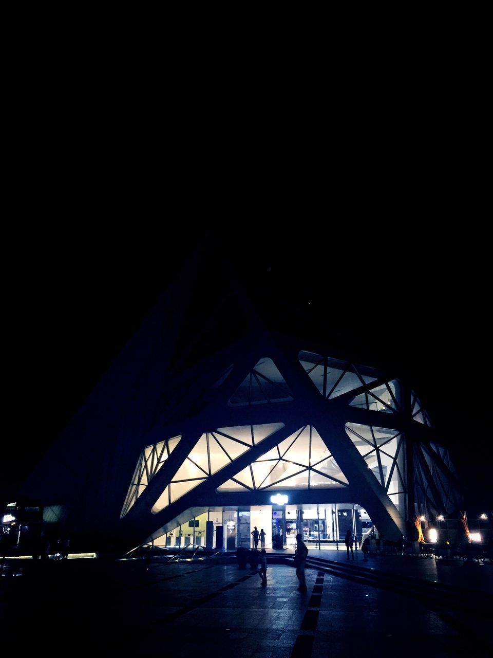 SILHOUETTE PERSON WALKING ON ILLUMINATED ROAD AT NIGHT