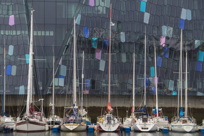 Sailboats moored in harbor by building