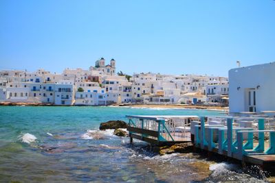 View of buildings by sea against clear blue sky