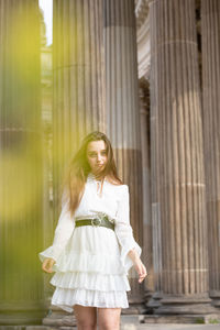 Portrait of young woman standing against columns