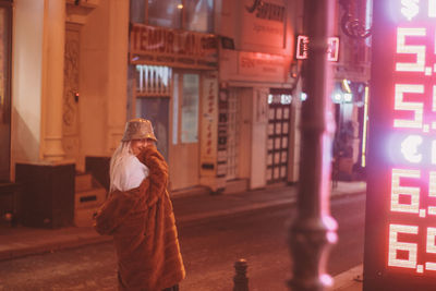 Rear view of woman standing on street against building in city