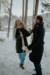 Smiling couple dancing while standing during winter in forest