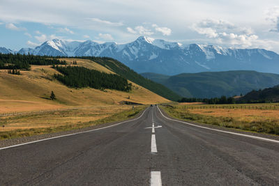 Road leading towards mountains against sky