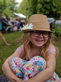 Smiling girl wearing hat sitting on land in park