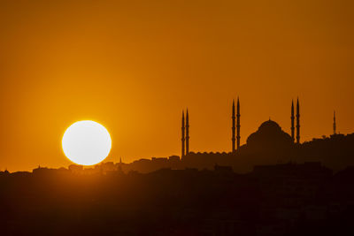 Silhouette built structure against orange sky