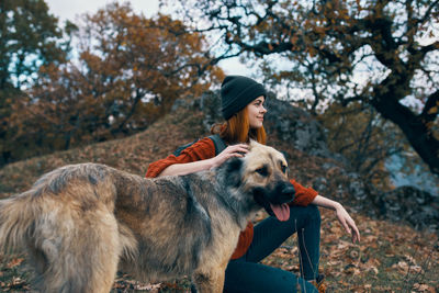 Full length of woman with dog against trees