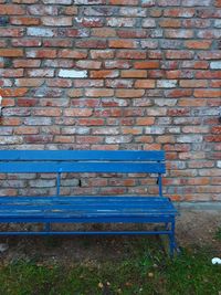 Empty bench against brick wall