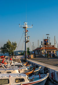 Boats moored at harbor against clear blue sky