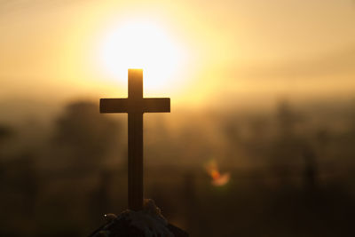 Close-up of cross at cemetery against sky during sunset
