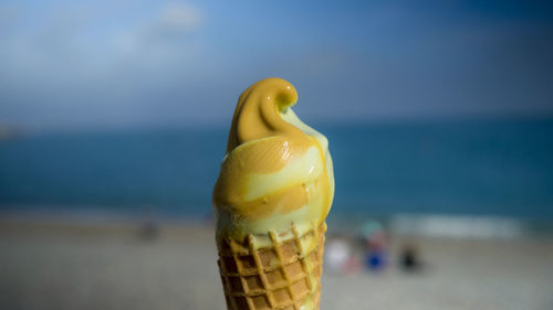 Close-up of ice cream on beach against sky