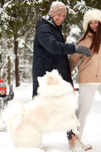 Side view of couple with dog on snow