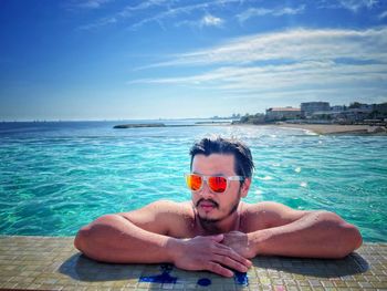 Portrait of shirtless man swimming in sea against sky