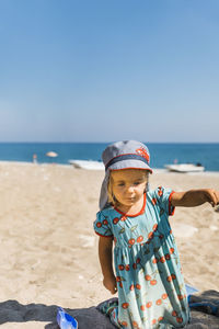 Boy wearing sunglasses on beach against clear sky