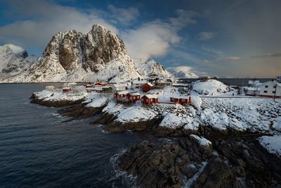 Scenic view of sea by mountain against sky