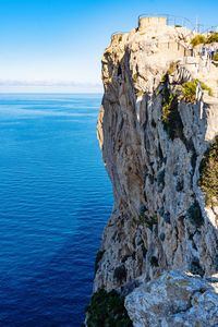 Rock formation by sea against blue sky