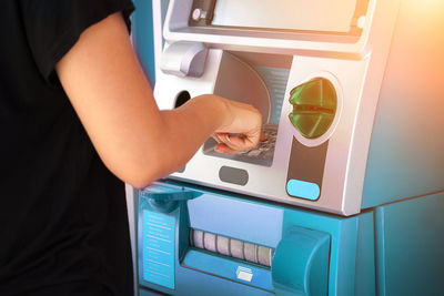 Midsection of woman using atm machine