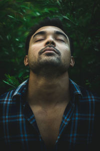 Close-up of young man standing against plants