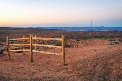 Fence on field against sky during sunset