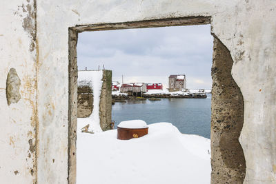 Snowy harbour seen through a doorway ruin arch