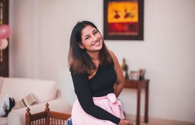 Portrait of smiling young woman sitting at home