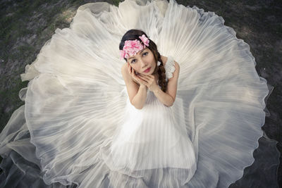 Portrait of young woman in white dress sitting outdoors